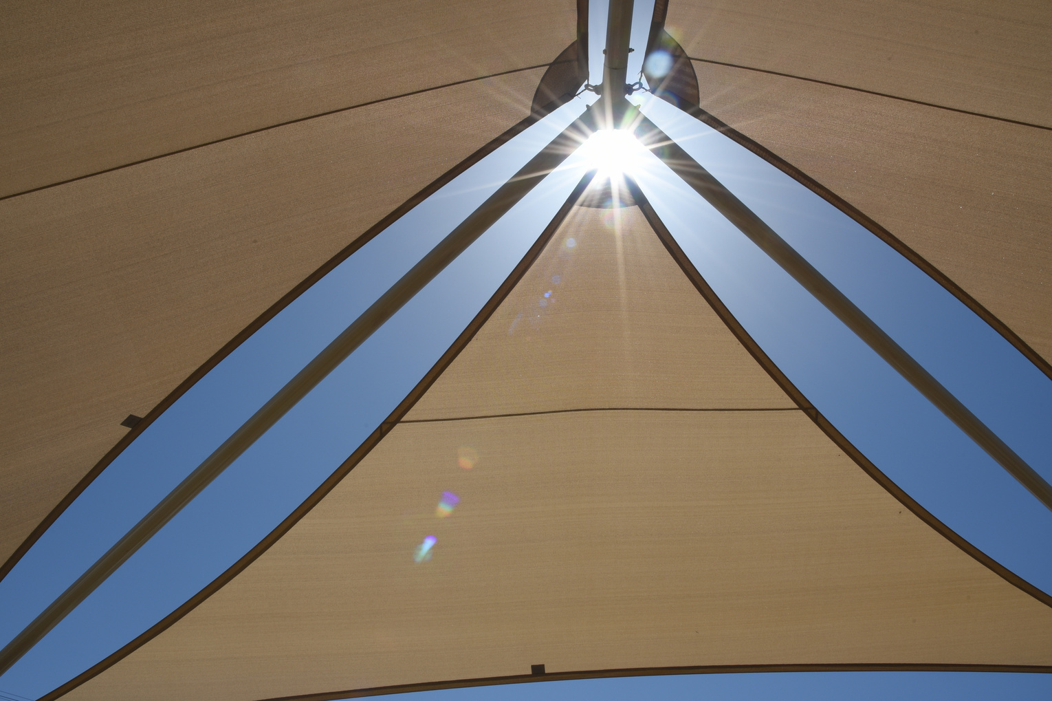 Dreieckige Sonnensegel vor blauem Himmel.